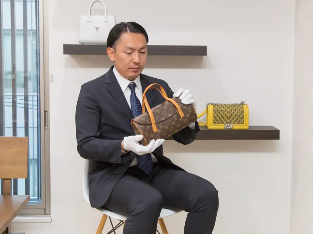 店でヴィトンのバッグを手袋で持って確かめている鑑定士の写真