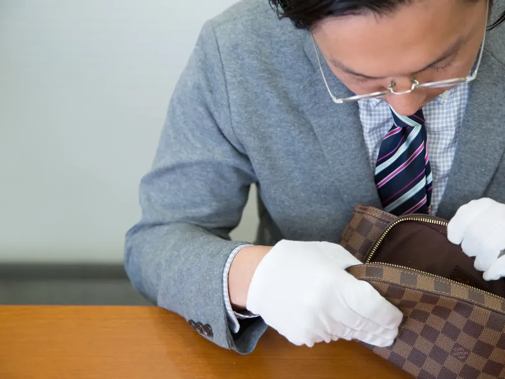 ヴィトンのバッグの内側を、顔を近づけて確かめている写真