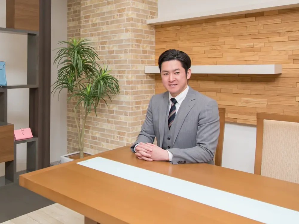 スーツ姿の鑑定士が、テーブルで落ち着いて座っている写真