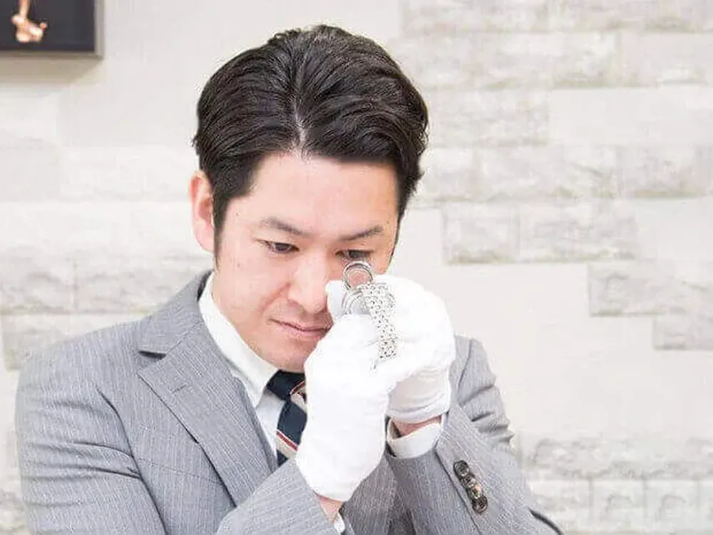 鑑定士が、ブレスレットをルーペで間近に確かめている写真